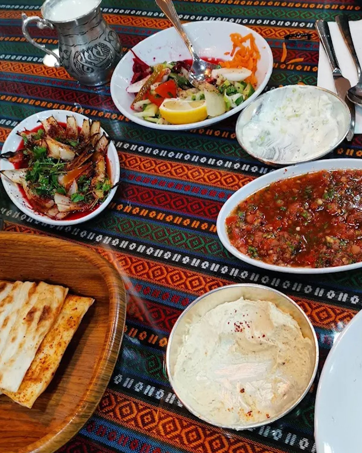Table spread at Kelebek — mezze, salads, dips and bread on a patterned cloth