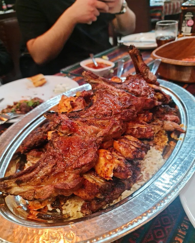 A silver platter of lamb chops and ribs served over rice